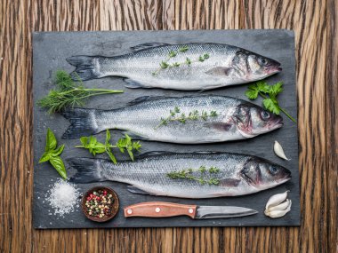 Seabass on a graphite board with spices and herbs. clipart