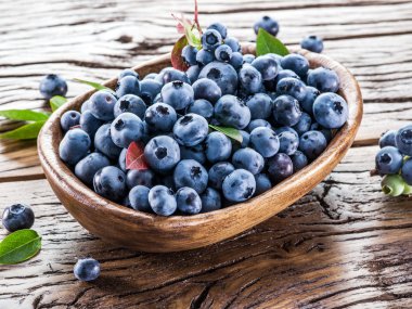 Ahşap masa üzerinde kapta olgun yaban mersini.