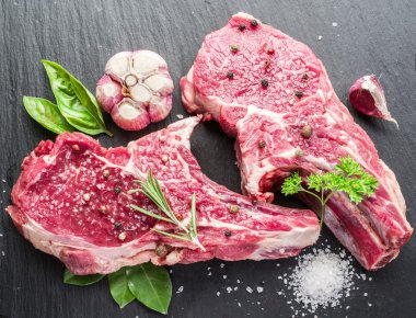 Ham beaf biftek siyah kesme tahtası üzerinde baharatlar ile.