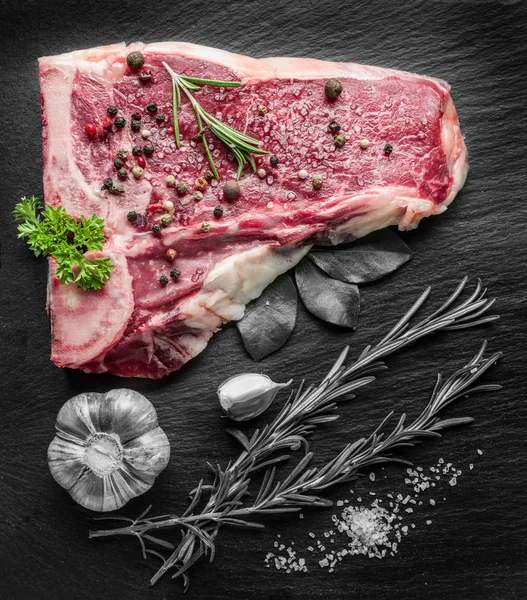 Steaks de bœuf cru aux épices sur la planche à découper noire . — Photo
