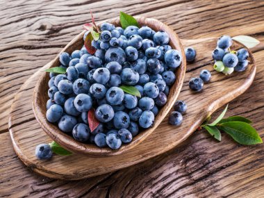 Ahşap masa üzerinde kapta olgun yaban mersini.