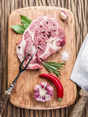 Ahşap kesme tahtası üzerinde baharatlar ile çiğ domuz eti biftek.