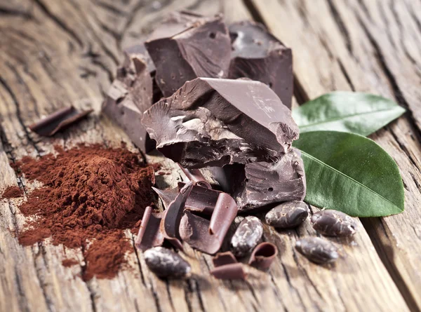 Chocolate and cocoa bean over wooden table. — Stock Photo, Image