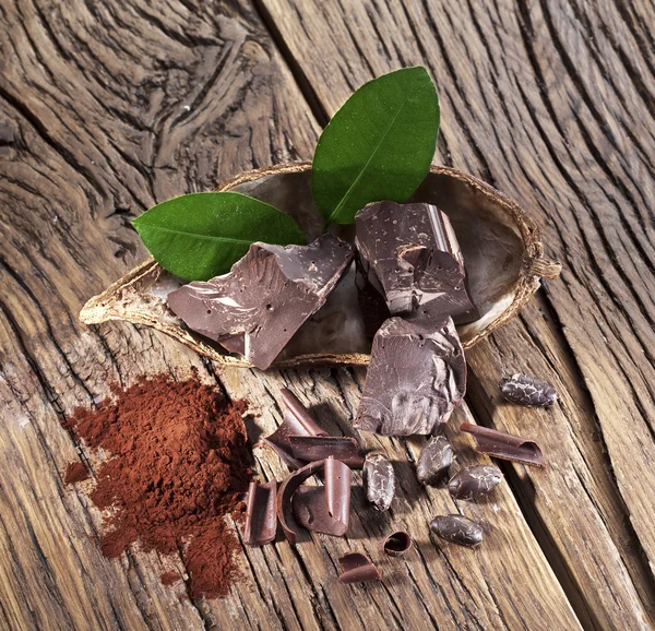 Chocolade en cacao bonen over houten tafel. — Stockfoto