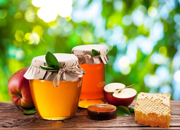 Glass cans full of honey, apples and combs. Stock Photo