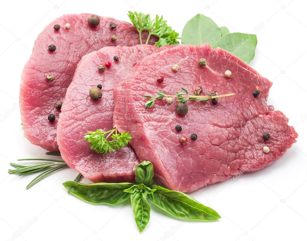 Raw beaf steaks with spices on a white background.