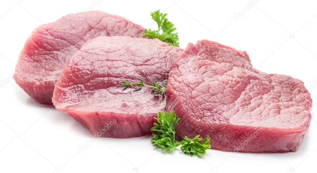 Raw beaf steaks with parsley on a white background.
