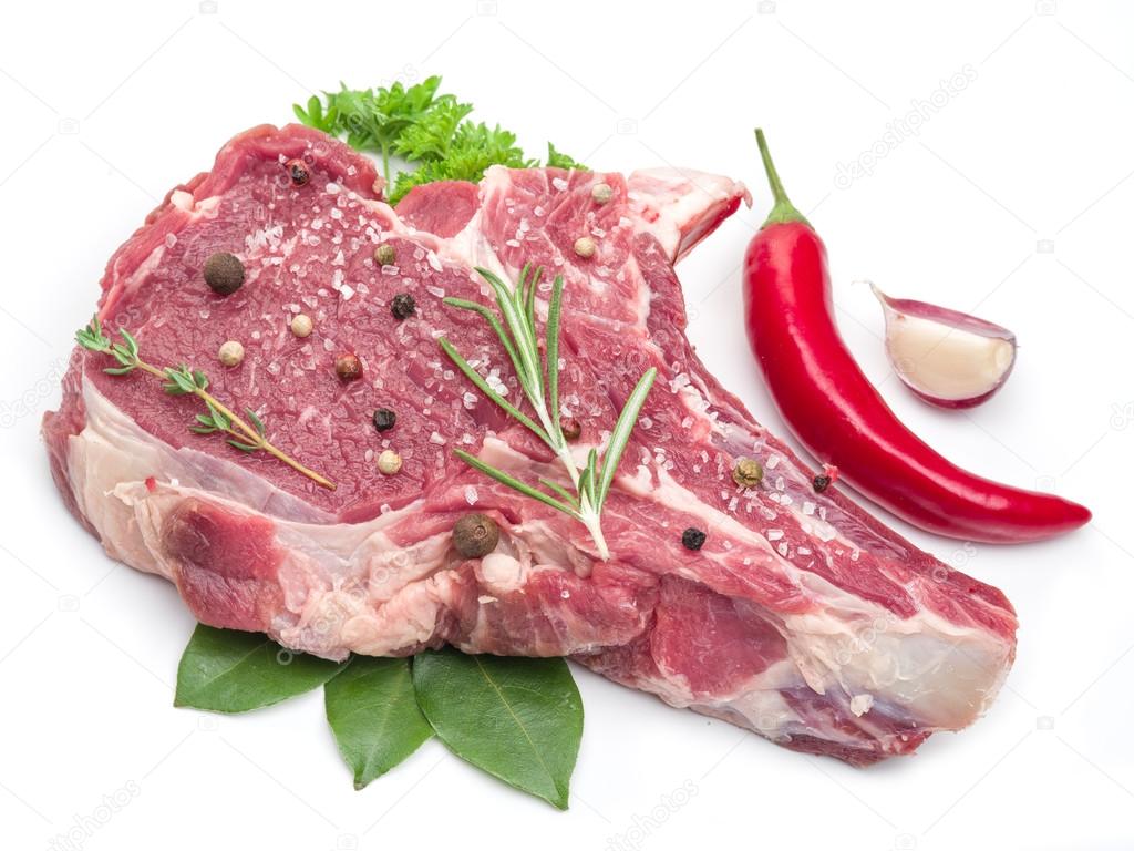 Raw beef steak with spices on the white background.