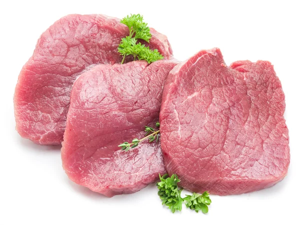 Rå nötkött biffar med persilja på vit bakgrund. — Stockfoto