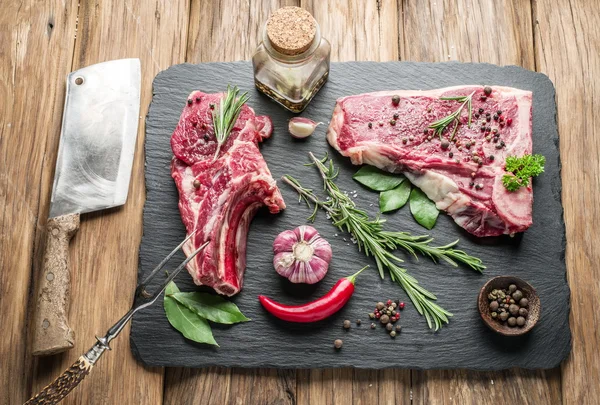 Raw beaf steaks with spices on black cutting board. Stock Photo by  ©Valentyn_Volkov 81018322