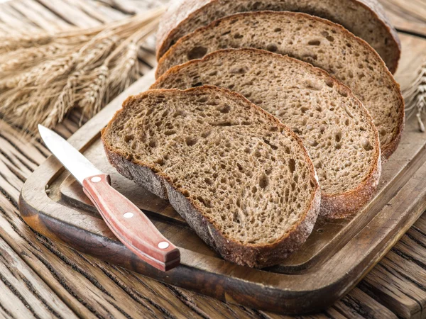 Zwart brood gesneden op de houten plank. — Stockfoto