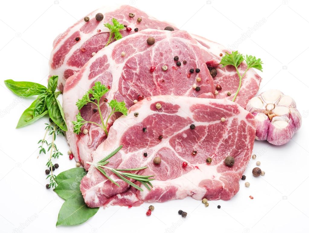 Raw pork meat steaks with spices on the white background.