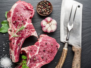Ham beaf biftek siyah kesme tahtası üzerinde baharatlar ile.