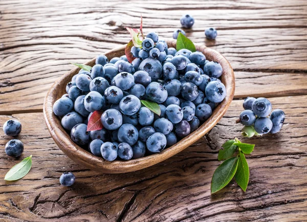 Ripe blueberries in the bowl on the wooden table. — Stock Photo, Image