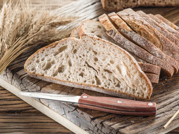 Skivad svart bröd på plankan. — Stockfoto