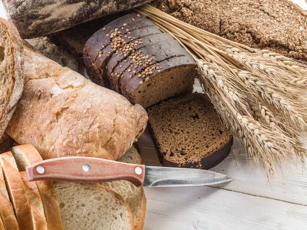 Het brood en een tarwe op de houten bureau. — Stockfoto