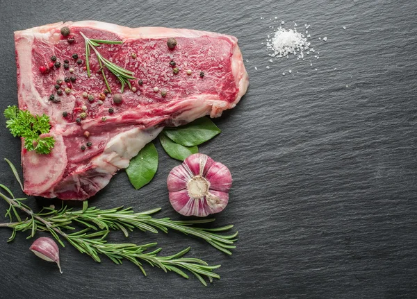 Bifes crus com especiarias na tábua de corte preta . — Fotografia de Stock