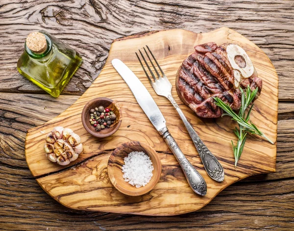 Rundvlees steaks met kruiden op een houten dienblad. — Stockfoto