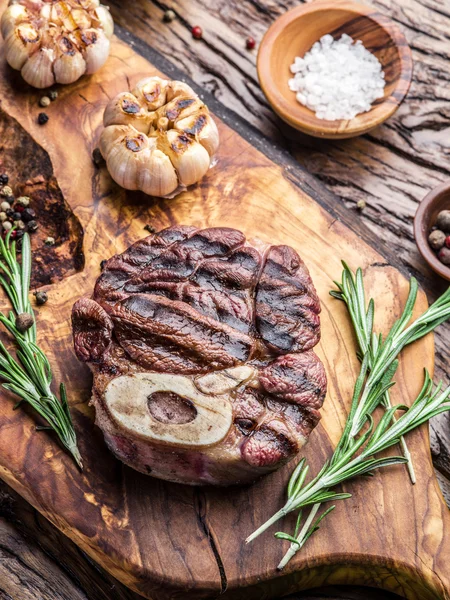 Rundvlees steaks met kruiden op een houten dienblad. — Stockfoto