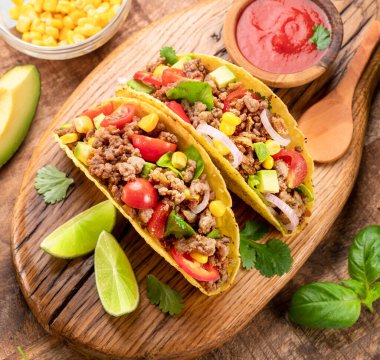 Tahta servis tahtasının yanında Meksika usulü et, tortilla ve limon dilimleri.. 