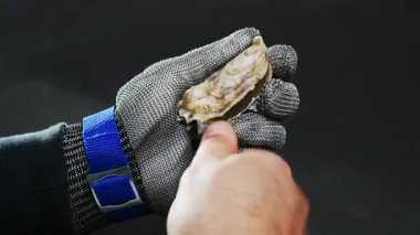 Çiğ istiridye işlemini başlatan adam özel bir eldivenle istiridye açıyor. Kapat..