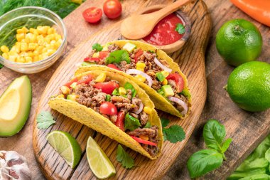 Tahta servis tahtasının yanında Meksika usulü et, tortilla ve limon dilimleri.. 