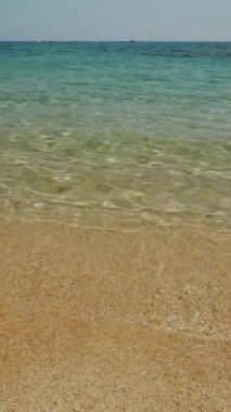 Sakin bir sahil seviyesinden deniz suyuna ve kıyıya yaklaşan ışık dalgalarına bak..