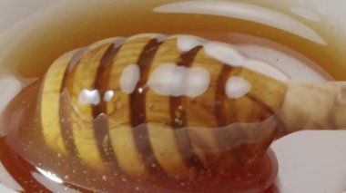 Bal damlaları yavaşça ahşap bal kabından bal kabına akıyor; yakın plan; yavaş çekim. 