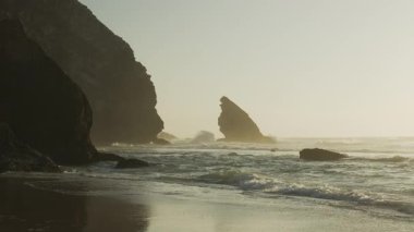 Günbatımında Atlantik Okyanusu 'nun Adraga plajı, Sintra Portekiz. Güneş, su yüzeyine parlak bir yol ile yansıdı. Yavaş çekim videosu. 