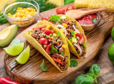 Tahta servis tahtasının yanında Meksika usulü et, tortilla ve limon dilimleri..