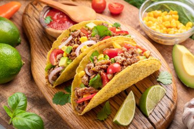 Tahta servis tahtasının yanında Meksika usulü et, tortilla ve limon dilimleri..