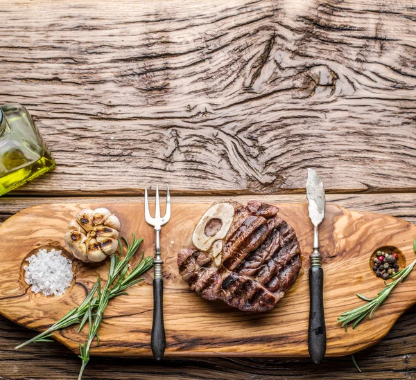 Rundvlees steaks met kruiden op een houten dienblad. — Stockfoto