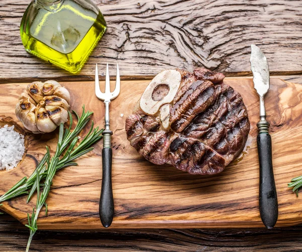 Rundvlees steaks met kruiden op een houten dienblad. — Stockfoto