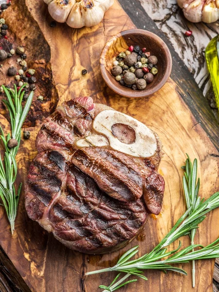 Rundvlees steaks met kruiden op een houten dienblad. — Stockfoto