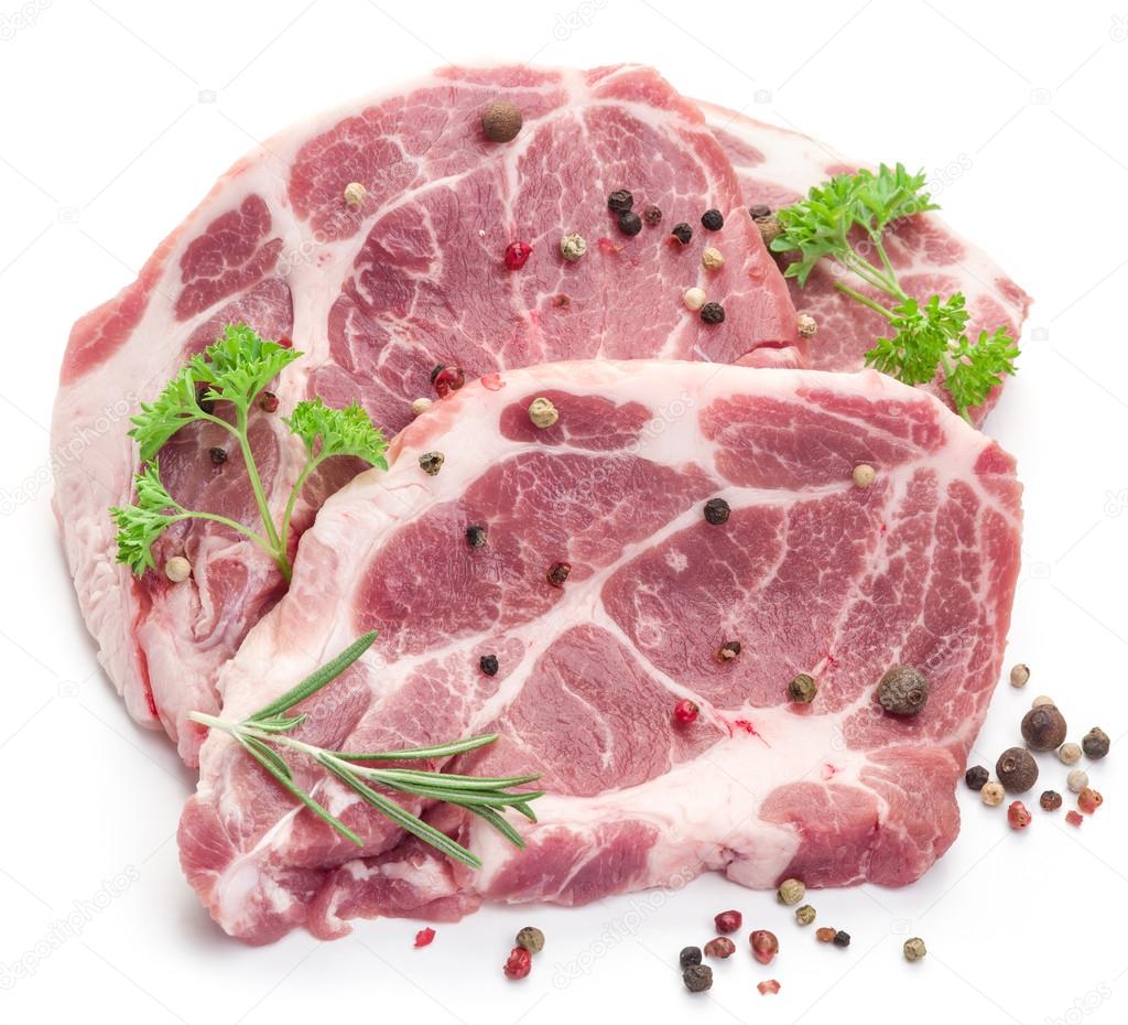 Raw pork meat steaks with spices on the white background.