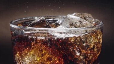 Siyah arka planda görünen köpüklü, köpüklü ve yükselen karbonat baloncuklu Cola cam kapaklı yakın çekim..