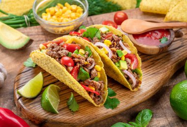 Tahta servis tahtasının yanında Meksika usulü et, tortilla ve limon dilimleri..