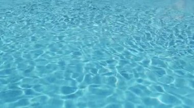 Havuzun suyunda dalgalanmalar. Şeffaf, ışıl ışıl ve hareketli suyun davetkar yüzeyi. Yukarıdan görüntüle.