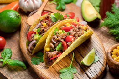 Tahta servis tahtasının yanında Meksika usulü et, tortilla ve limon dilimleri..