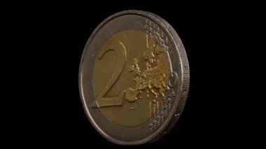 Siyah arkaplanda kendi eksenleri etrafında dönen iki avro sikke.