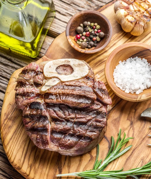 Rundvlees steaks met kruiden op een houten dienblad. — Stockfoto