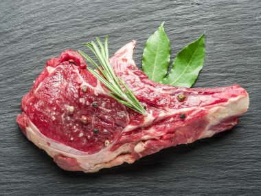 Ham sığır eti biftek siyah kesme tahtası üzerinde baharatlar ile.