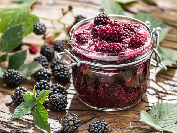 Brombeerkonfitüre auf altem Holztisch. mehrere frische Beeren sind in der Nähe. — Stockfoto