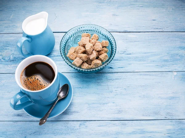 Ceașcă de cafea, ulcior de lapte și cuburi de zahăr din trestie . — Fotografie, imagine de stoc