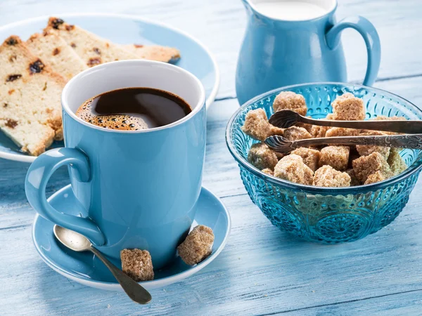 Tasse Kaffee, Milchkanne, Zuckerrohrwürfel und Obstkuchen. — Stockfoto