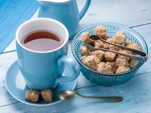 Taza de té, jarra de leche y cubos de azúcar de caña . — Foto de Stock