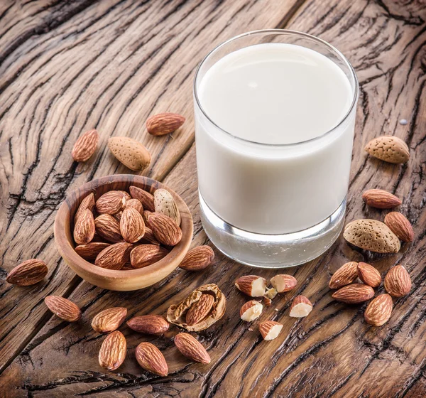 Nueces de almendra y leche sobre mesa de madera . — Foto de Stock