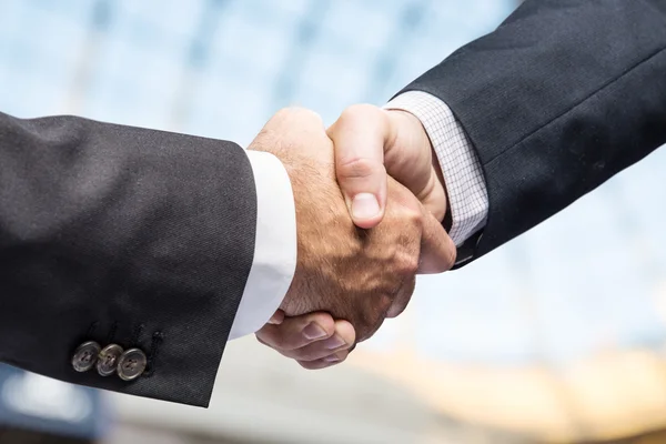 Handshake. Detailní záběr rukou. Obchodní centrum na pozadí. — Stock fotografie