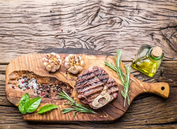 Rundvlees steaks met kruiden op een houten dienblad. — Stockfoto