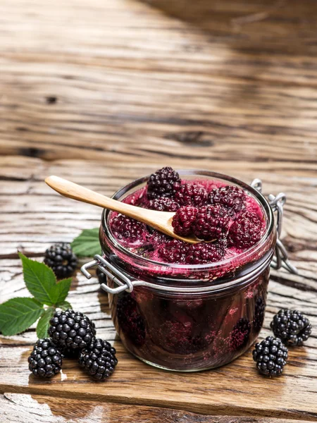 Confiture de mûres sur une vieille table en bois. Plusieurs baies fraîches sont à proximité . — Photo